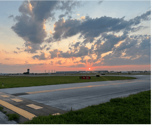 A view of an airport runway at sunset.