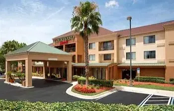 A hotel with palm trees and parking lot.