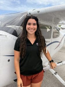 Smiling woman leaning on white training aircraft